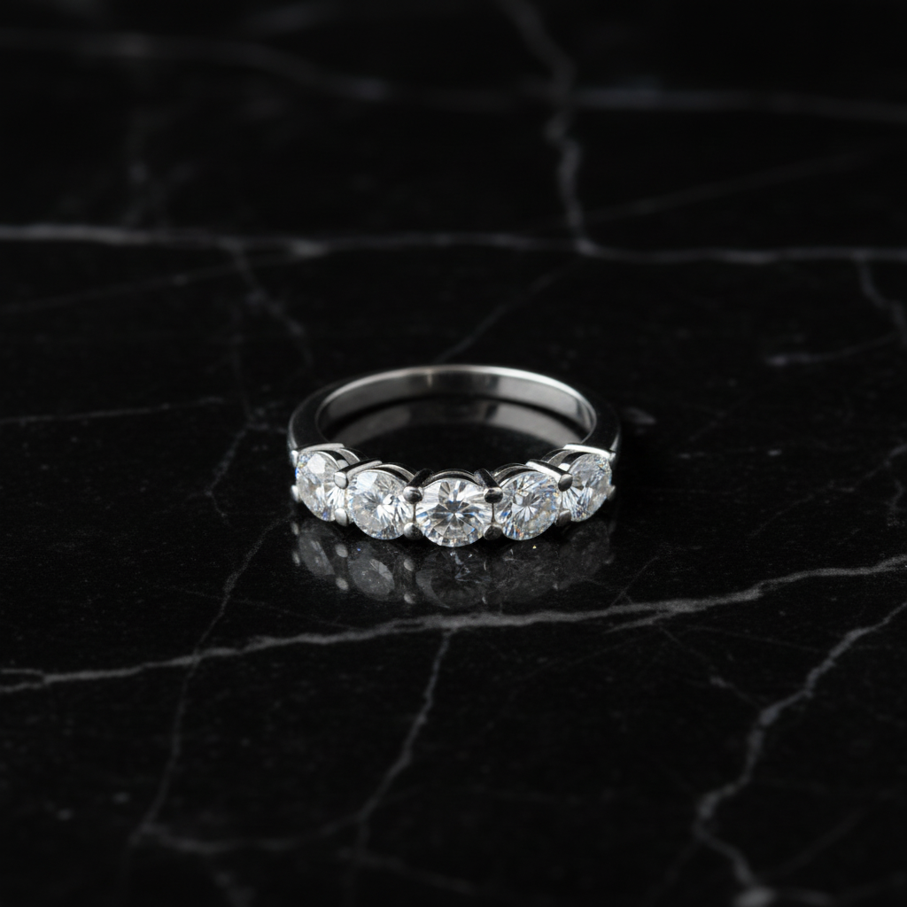 Five-stone diamond ring laying flat on black marble